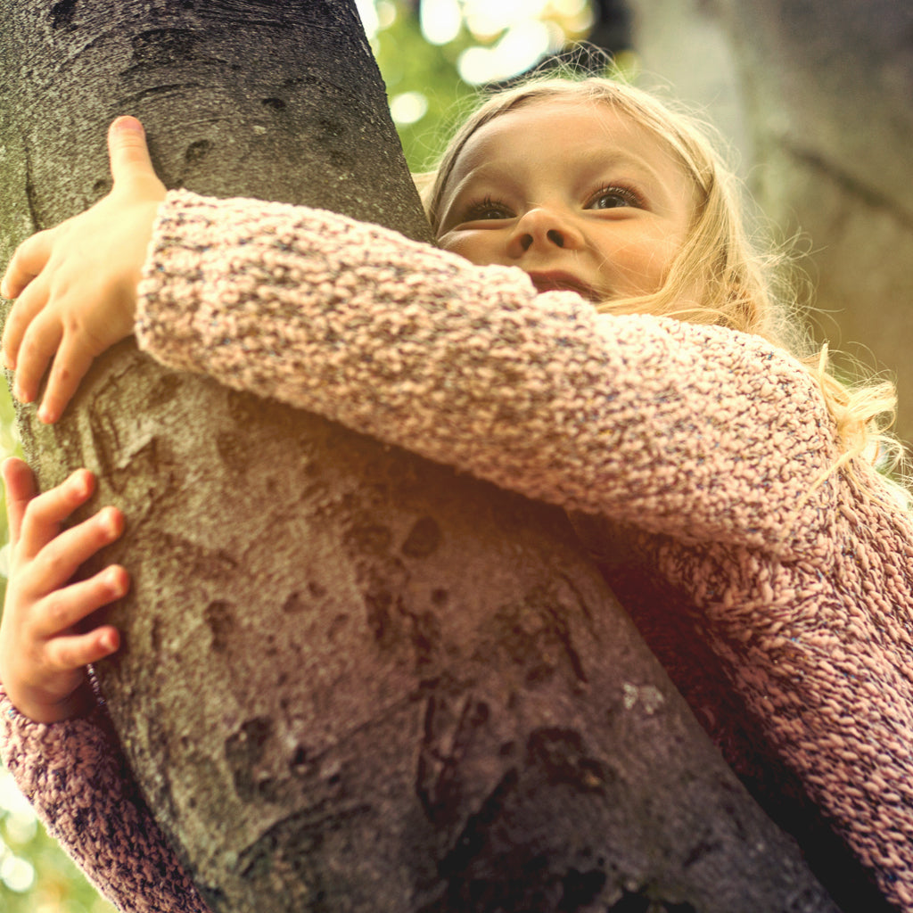 Little girl hugging a tree